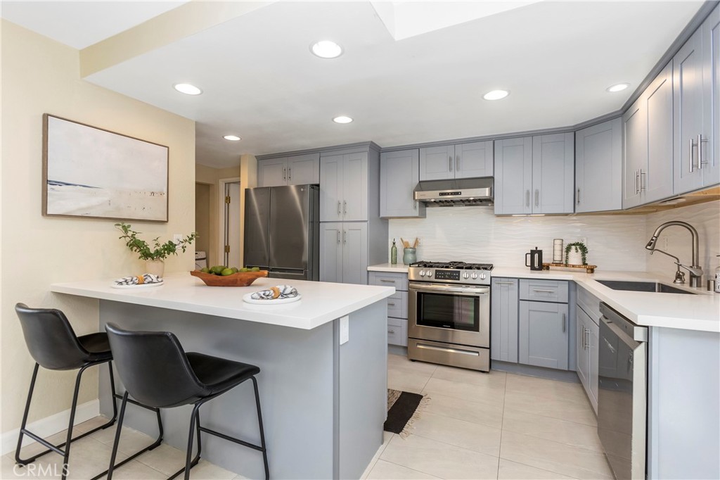 249 Mountain Court Brea, CA 92821 - Photo 8 of 37 a kitchen with stainless steel appliances a stove a sink a refrigerator and white cabinets with wooden floor
