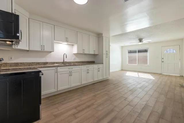 a kitchen with granite countertop a stove a sink and a microwave