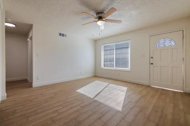 an empty room with windows and a ceiling fan