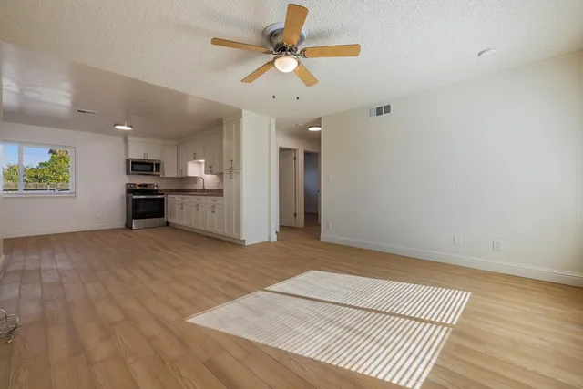 a view of a kitchen with a stove cabinets wooden floor and a ceiling fan