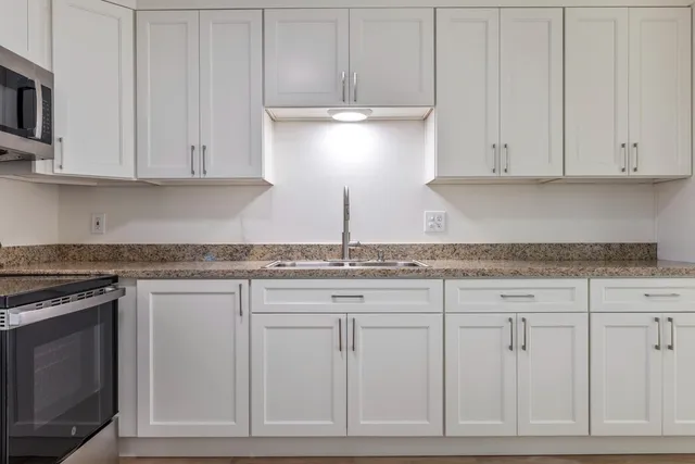 a kitchen with granite countertop white cabinets and a stove