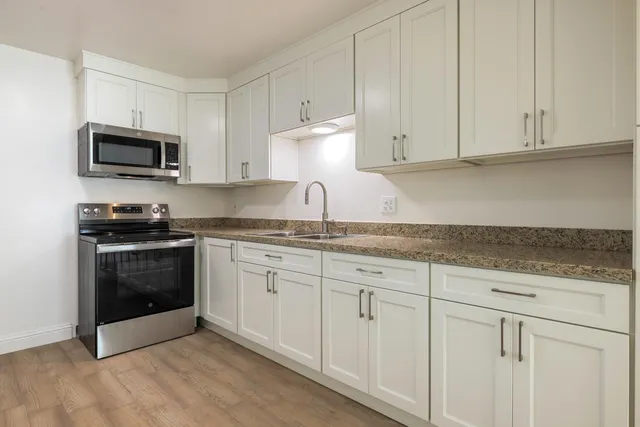 a kitchen with granite countertop white cabinets and stainless steel appliances