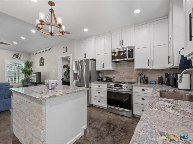 a kitchen with stainless steel appliances granite countertop a stove top oven a sink dishwasher and white cabinets with wooden floor