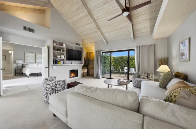 a living room with furniture a large window a flat screen tv and a chandelier