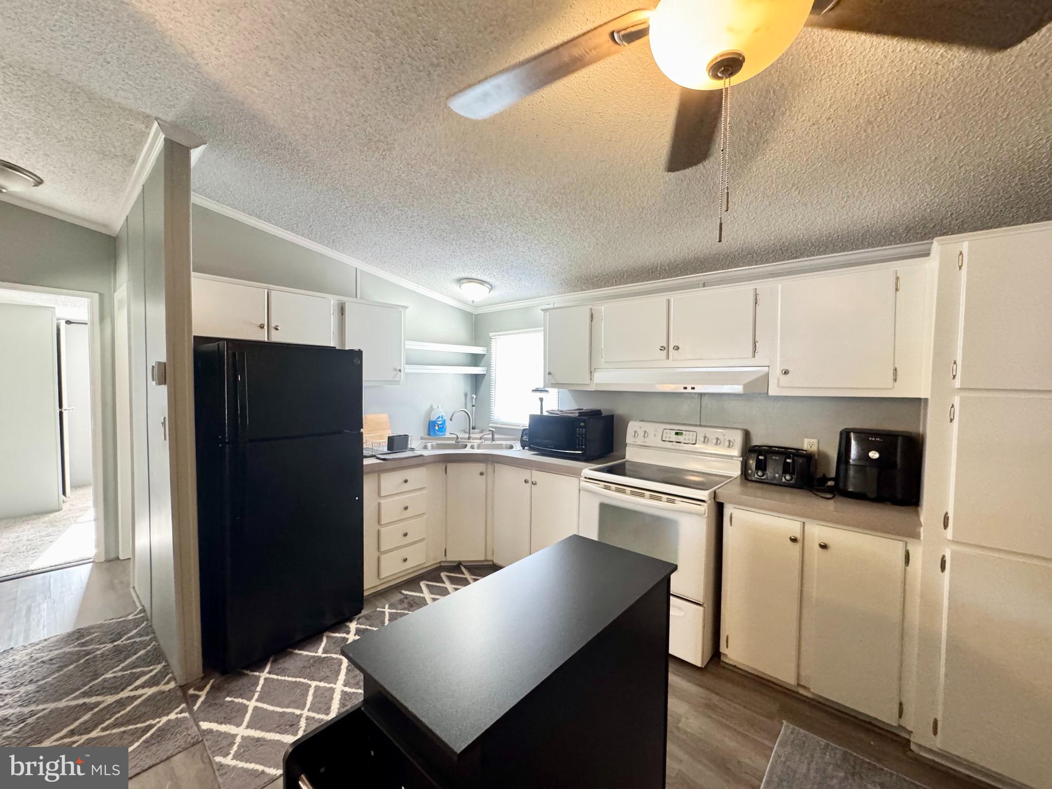 9333 Colonial Mill Drive Delmar, MD 21875 - Photo 9 of 31 a kitchen with a refrigerator a stove and white cabinets with wooden floor