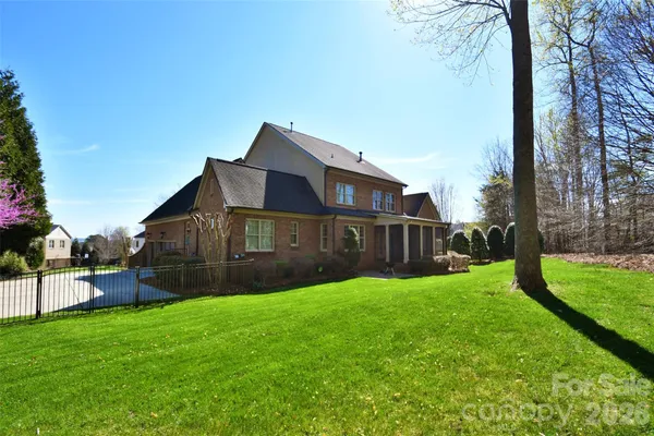 a view of a house next to a big yard and large trees