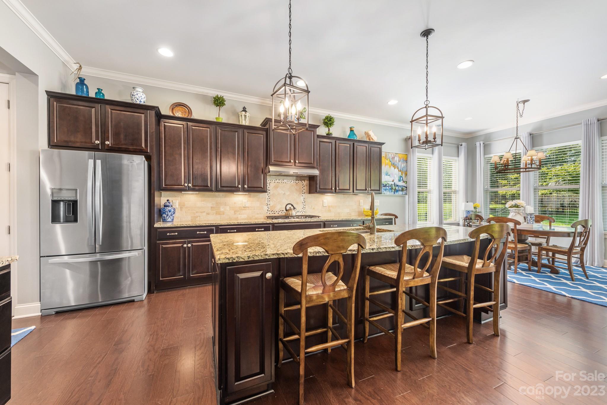 9006 Blue Ridge Drive Indian Land, SC 29707 - Photo 11 of 27 a kitchen with stainless steel appliances granite countertop a refrigerator a sink dishwasher a dining table and chairs with wooden floor