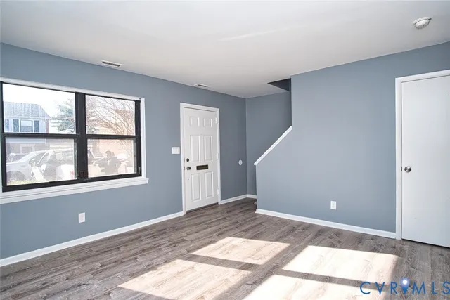 a view of empty room with wooden floor and fan