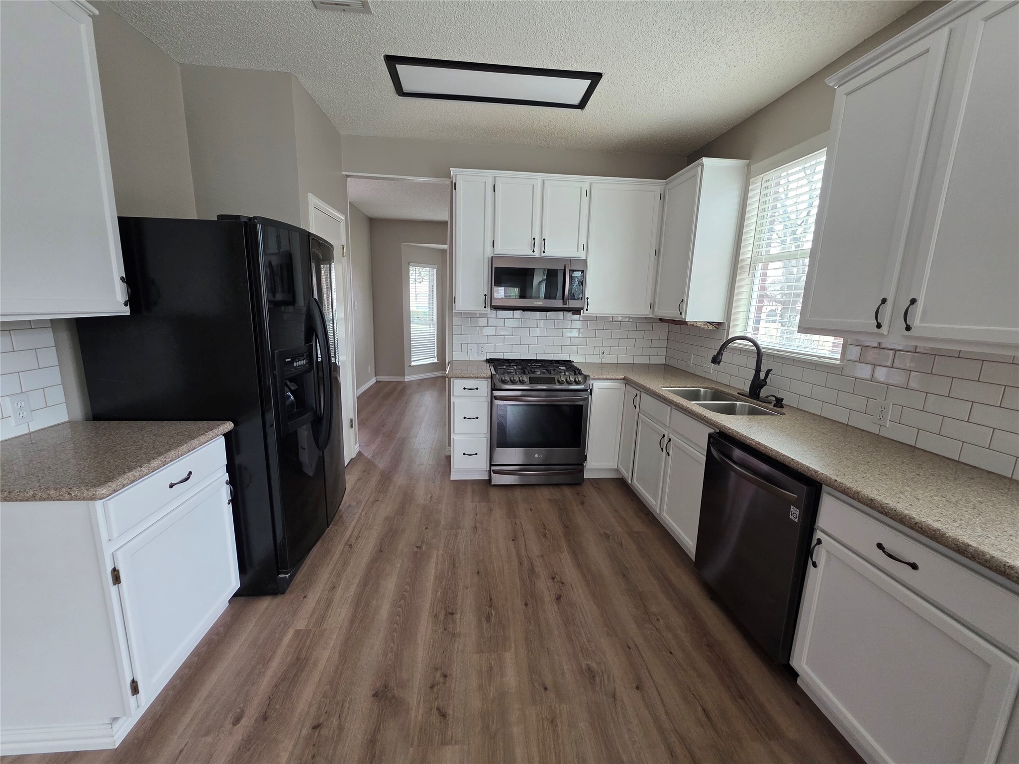 8507 Chat Lane Round Rock, TX 78681 - Photo 11 of 12 a kitchen with a sink a refrigerator a stove top oven a wooden floor and cabinets