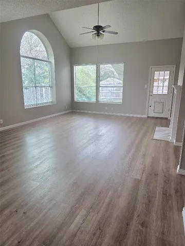 an empty room with wooden floor chandelier and windows