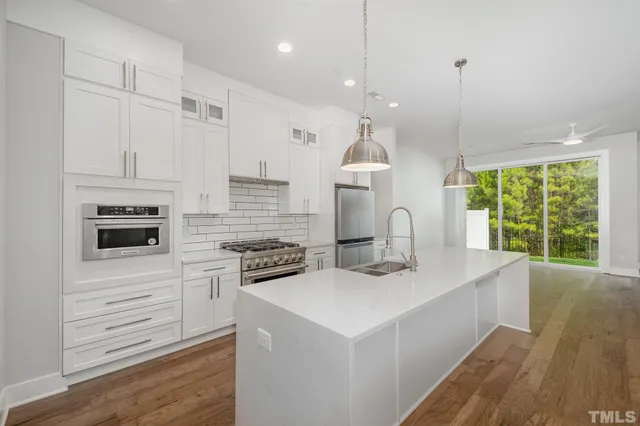 a kitchen with kitchen island a stove a sink a center island and wooden floor