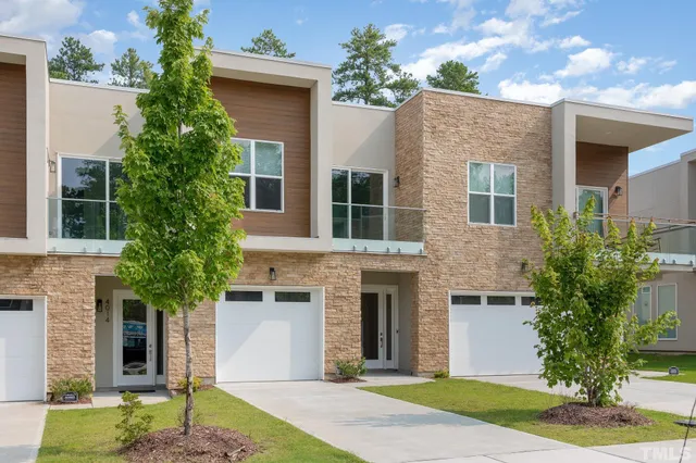 a front view of a house with a garden and trees
