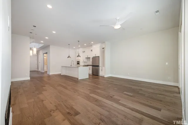 a view of kitchen and empty room with wooden floor