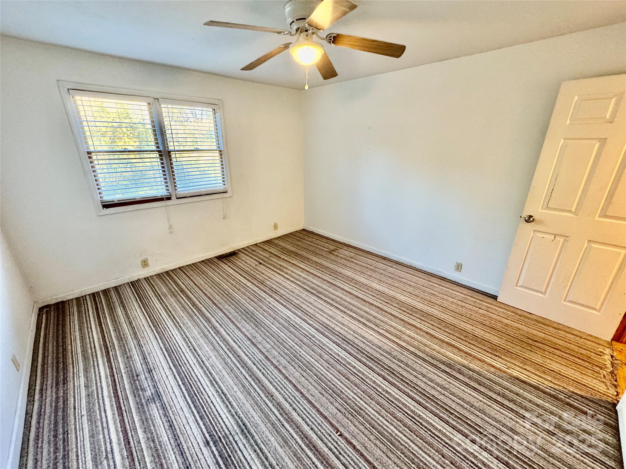 199 Bell Farm Road Statesville, NC 28625 - Photo 23 of 48 an empty room with wooden floor fan and windows