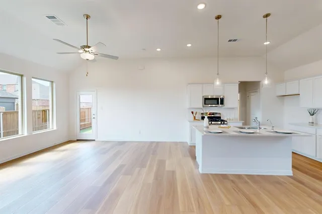 a view of kitchen with refrigerator stove and wooden floor