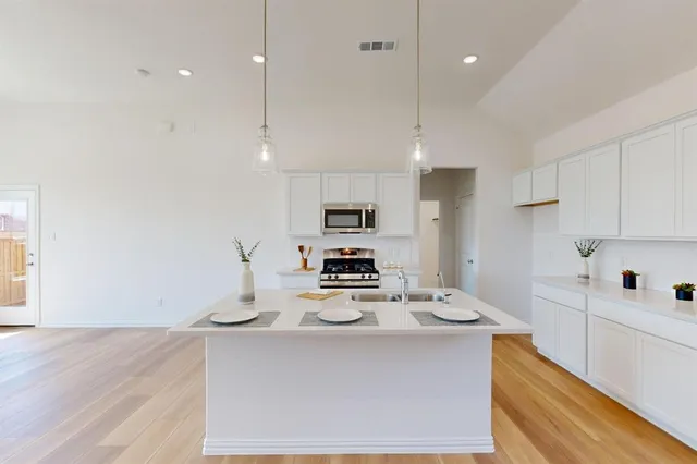 a kitchen with stainless steel appliances granite countertop a sink a stove and a refrigerator