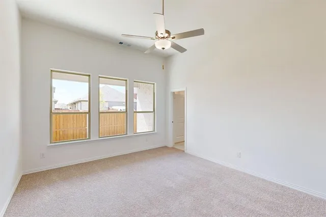 an empty room with a ceiling fan and window
