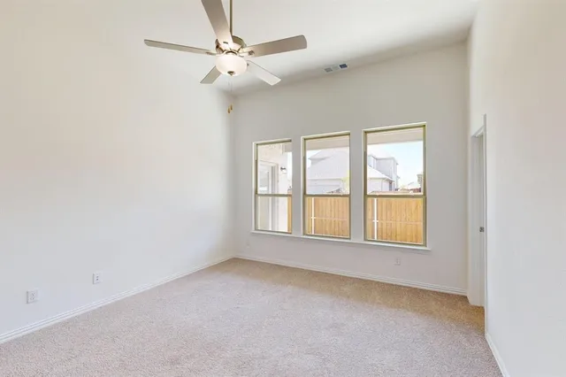 an empty room with chandelier fan and windows