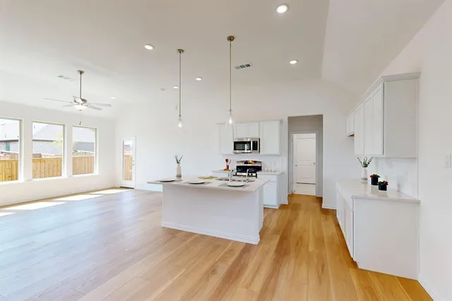 a large kitchen with stainless steel appliances a large counter top a sink a refrigerator and a window