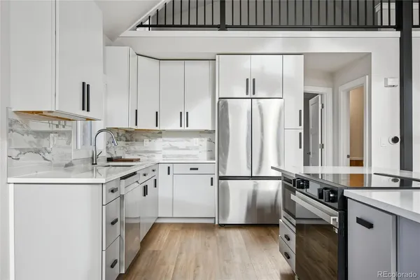 a kitchen with a sink a refrigerator and white cabinets