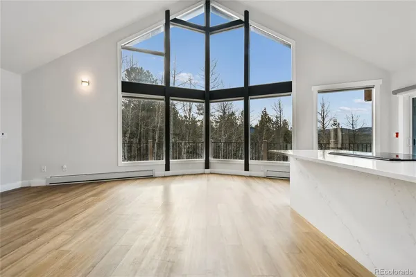 a view of an empty room with wooden floor and fan