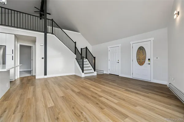 a view of an empty room with wooden floor and stairs