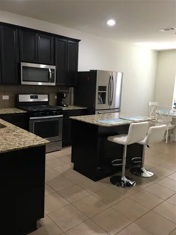 a kitchen with kitchen island granite countertop a stove top oven microwave and refrigerator