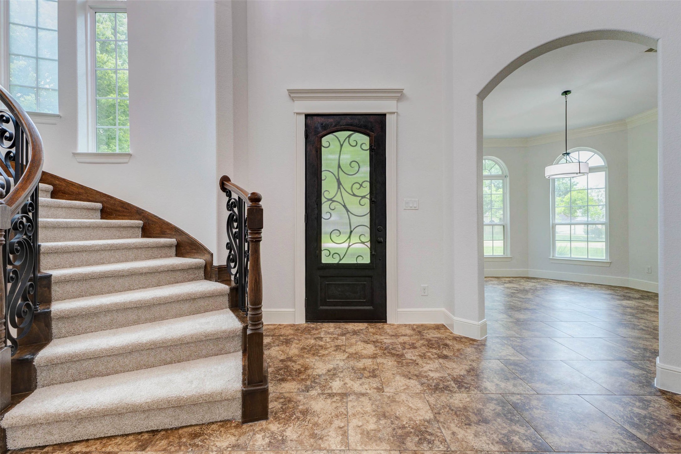 5327 Whitmore Fulshear, TX 77441 - Photo 6 of 50 Step through the stunning front door and into a grand foyer where soaring ceilings, gleaming tile flooring, and a dramatic spiral staircase immediately set the tone for the refined living that awaits.