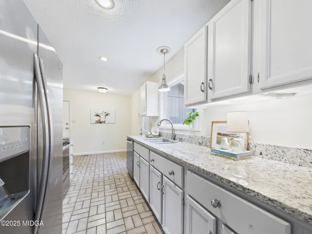 a kitchen with granite countertop a sink a stove a refrigerator and cabinets