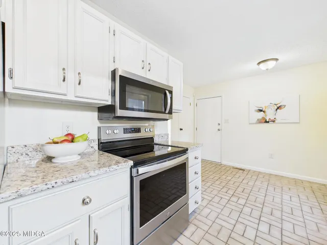 a kitchen with granite countertop a stove sink and microwave