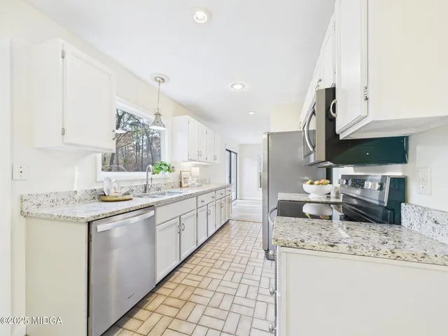 a kitchen with granite countertop a sink a stove and cabinets