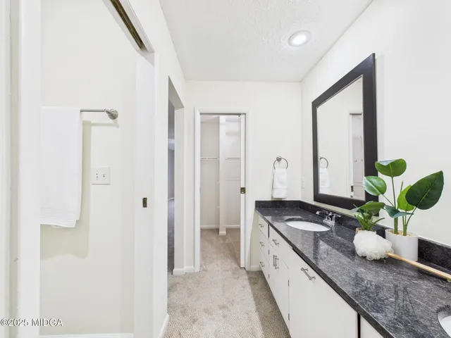 a large white kitchen with sink and stainless steel appliances