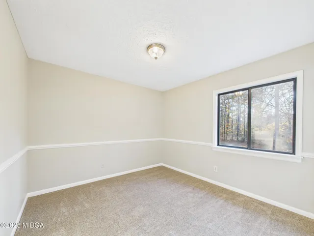 an empty room with windows and ceiling fan