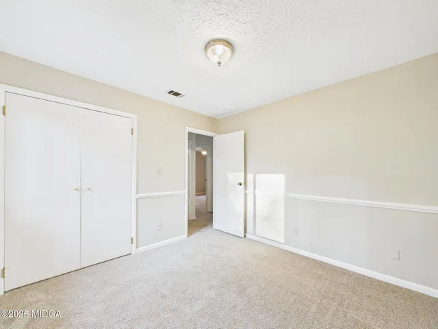an empty room with a chandelier fan and wooden floor
