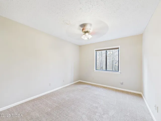 an empty room with a window and a fan