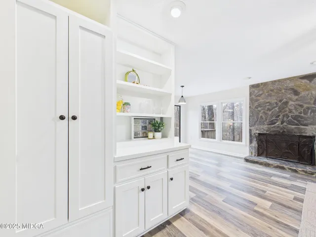 a hallway with white cabinets and wooden floor