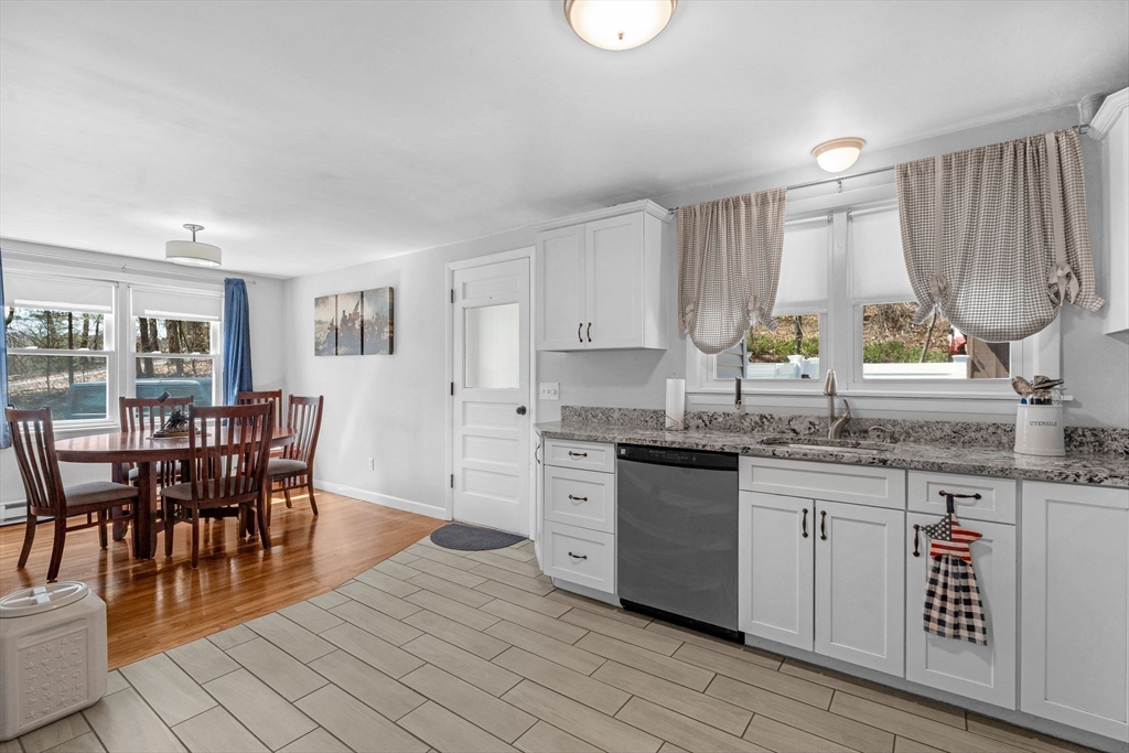 156 Andover Road Billerica, MA 01821 - Photo 8 of 22 a kitchen with stainless steel appliances granite countertop a stove top oven a sink dishwasher a dining table and chairs with wooden floor