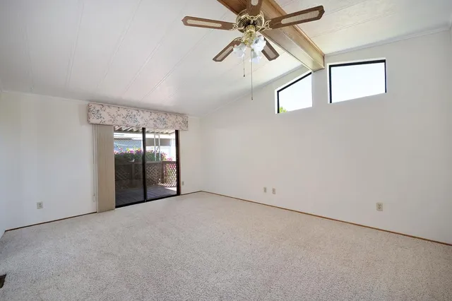 an empty room with chandelier fan and windows