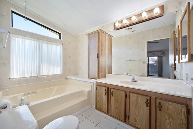 a bathroom with a granite countertop sink mirror bathtub and toilet