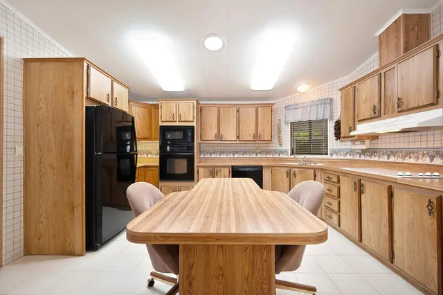 a kitchen with stainless steel appliances kitchen island granite countertop a refrigerator a sink dishwasher and wooden cabinets