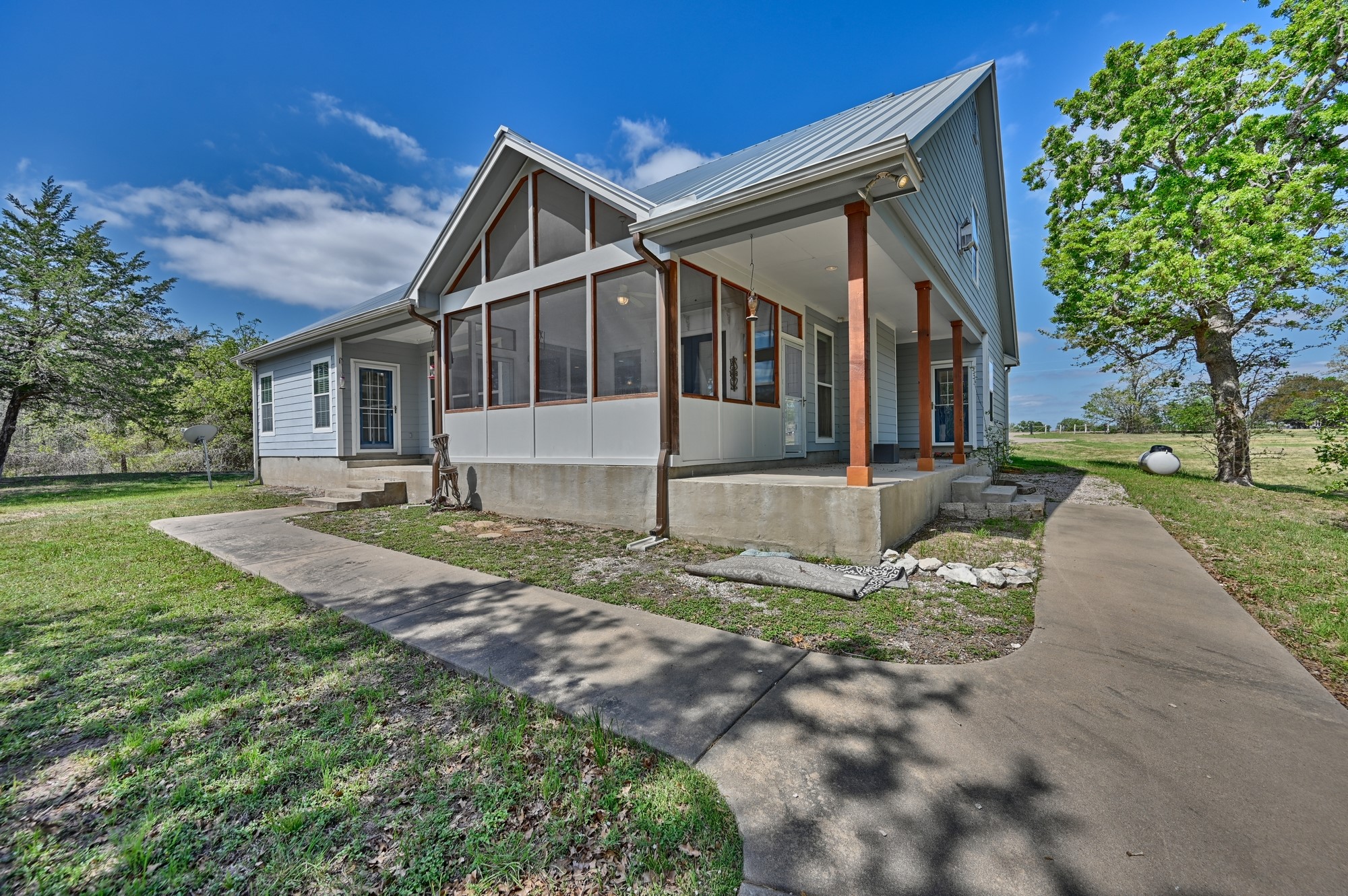 350 Owl Creek Road Giddings, TX 78942 - Photo 22 of 29 View of side of home with a yard, a sunroom, and a metal roof