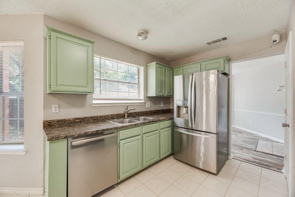 5610 Eagle Rock Road Arlington, TX 76017 - Photo 13 of 33 Kitchen featuring light green cabinetry, granite-finish countertops, and white tile flooring