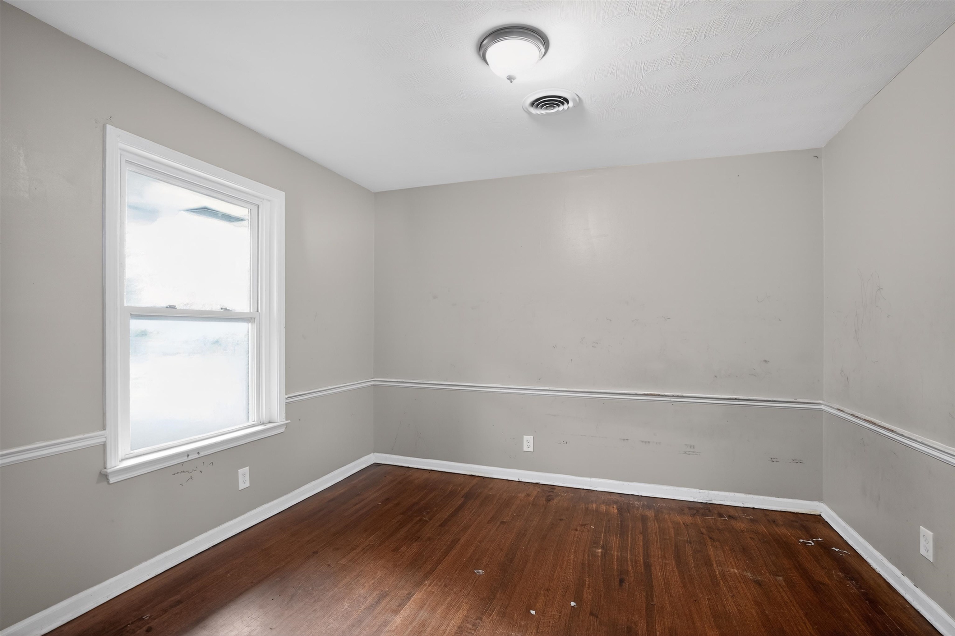1890 Pennel Road Memphis, TN 38116 - Photo 11 of 25 Room featuring wood-finish flooring, a double-hung window with white trim, and light gray walls with chair rail molding