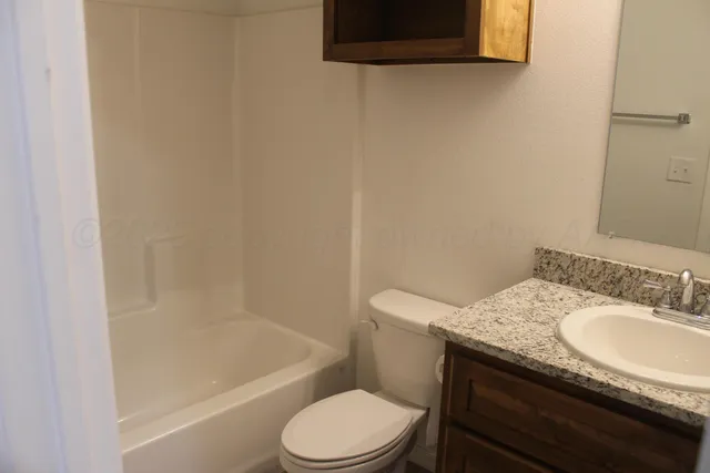 a bathroom with a granite countertop toilet sink and mirror