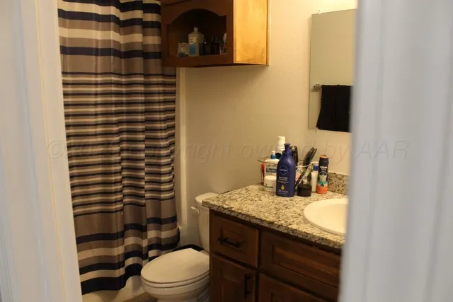 a bathroom with a granite countertop toilet sink and mirror