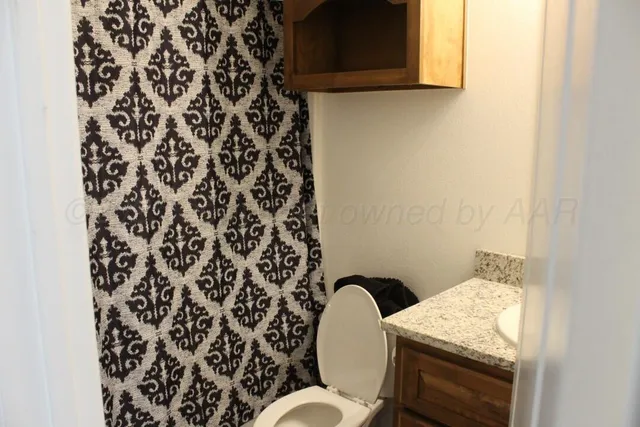 a bathroom with a granite countertop sink and a toilet