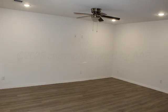 a view of a room with wooden floor ceiling fan and window