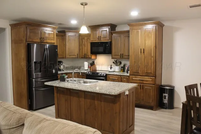 a kitchen with kitchen island a sink stainless steel appliances and cabinets