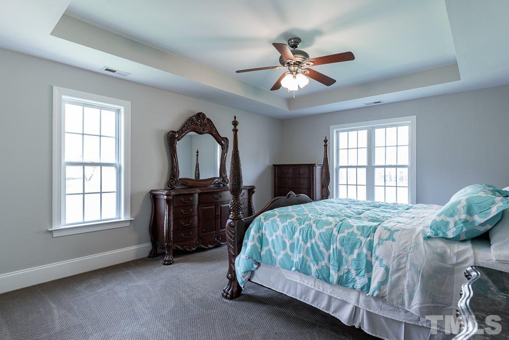 12708 Norwood Road Raleigh, NC 27613 - Photo 14 of 24 a bedroom with a bed and a chandelier