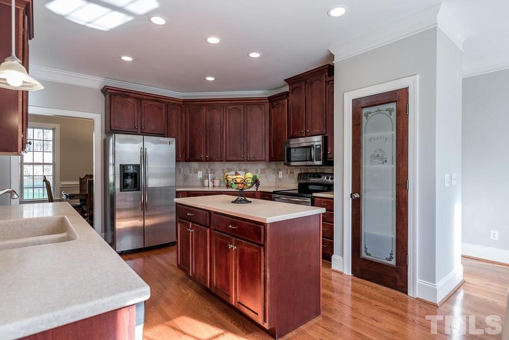 12708 Norwood Road Raleigh, NC 27613 - Photo 6 of 24 a kitchen with stainless steel appliances granite countertop a stove top oven a refrigerator and a sink with wooden floor